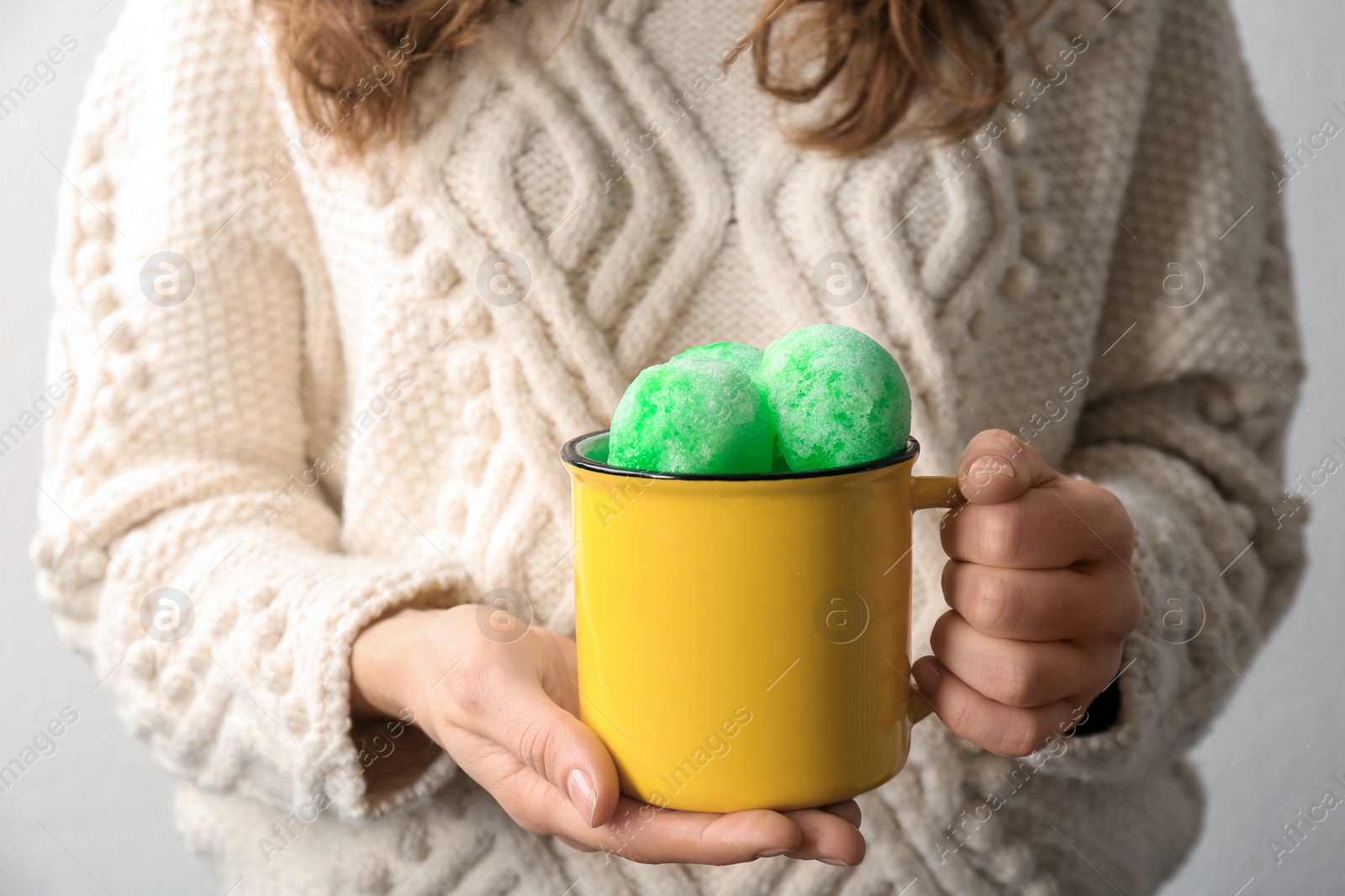 Photo of Woman with mug of snow ice cream on light background, closeup