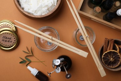 Photo of Flat lay composition with ingredients for homemade candles on brown background