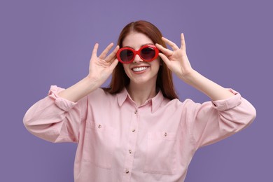 Photo of Portrait of smiling woman in sunglasses on purple background