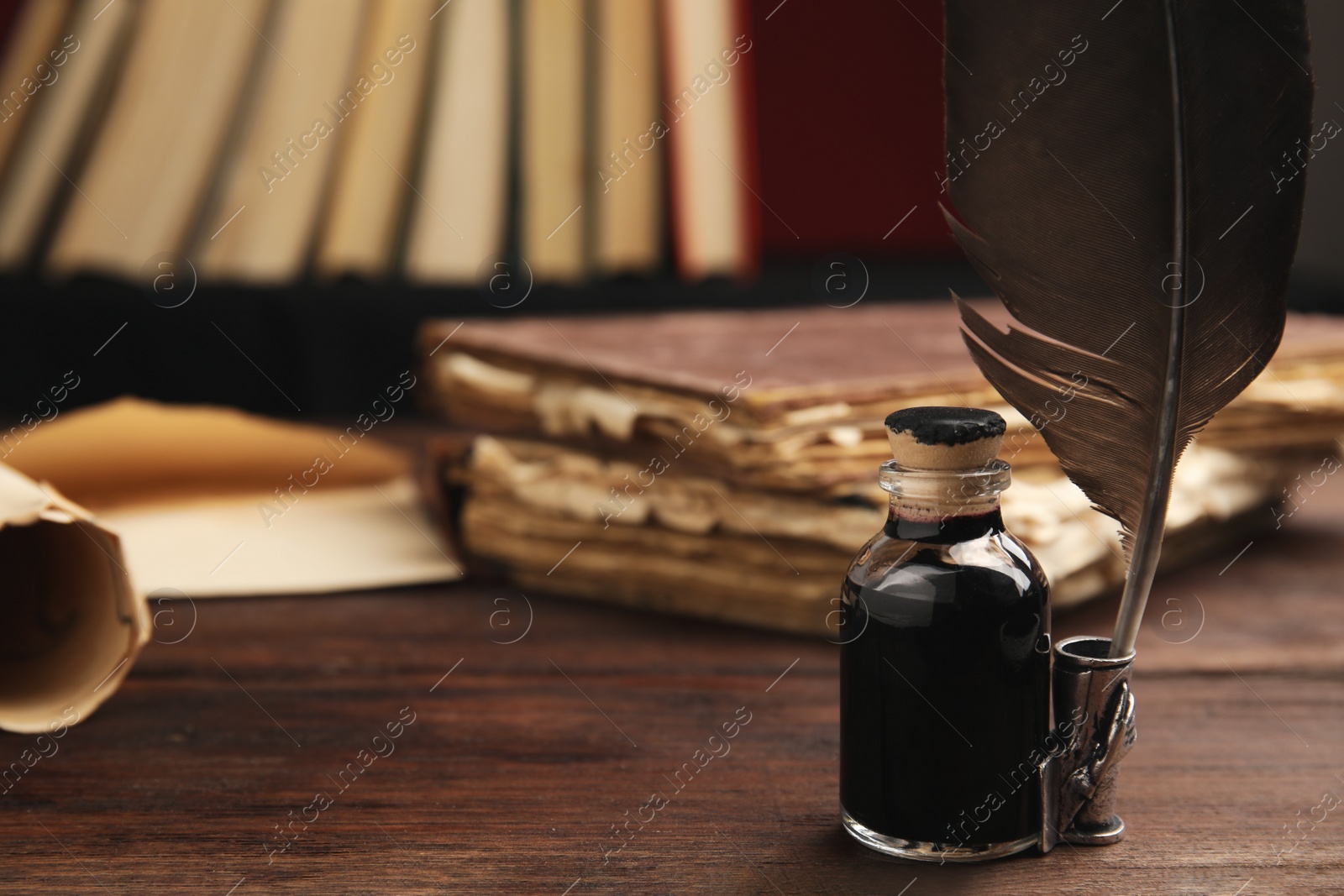 Photo of Feather pen and bottle of ink on wooden table. Space for text