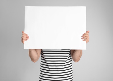 Man holding blank poster on light grey background