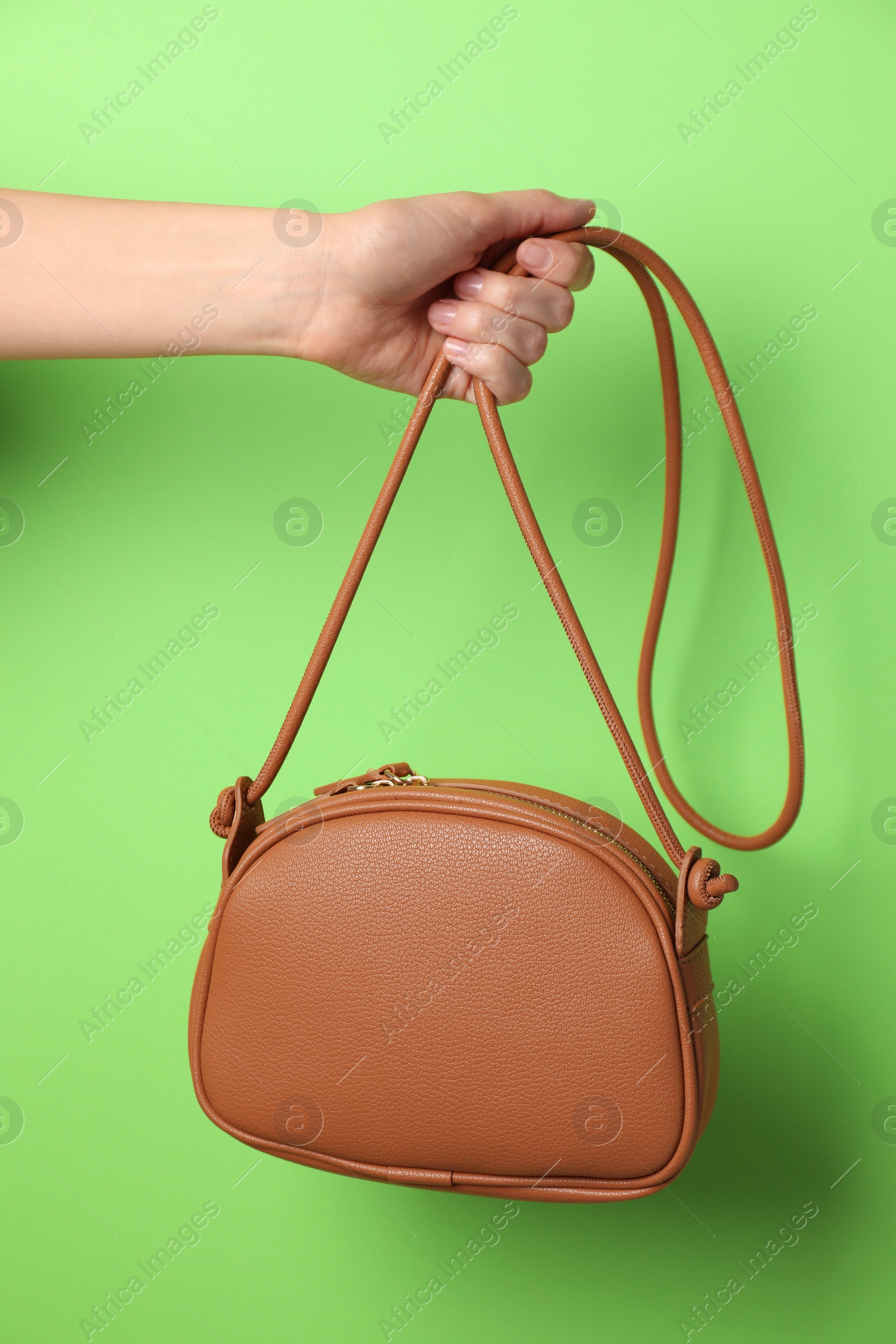 Photo of Woman holding stylish bag on green background, closeup