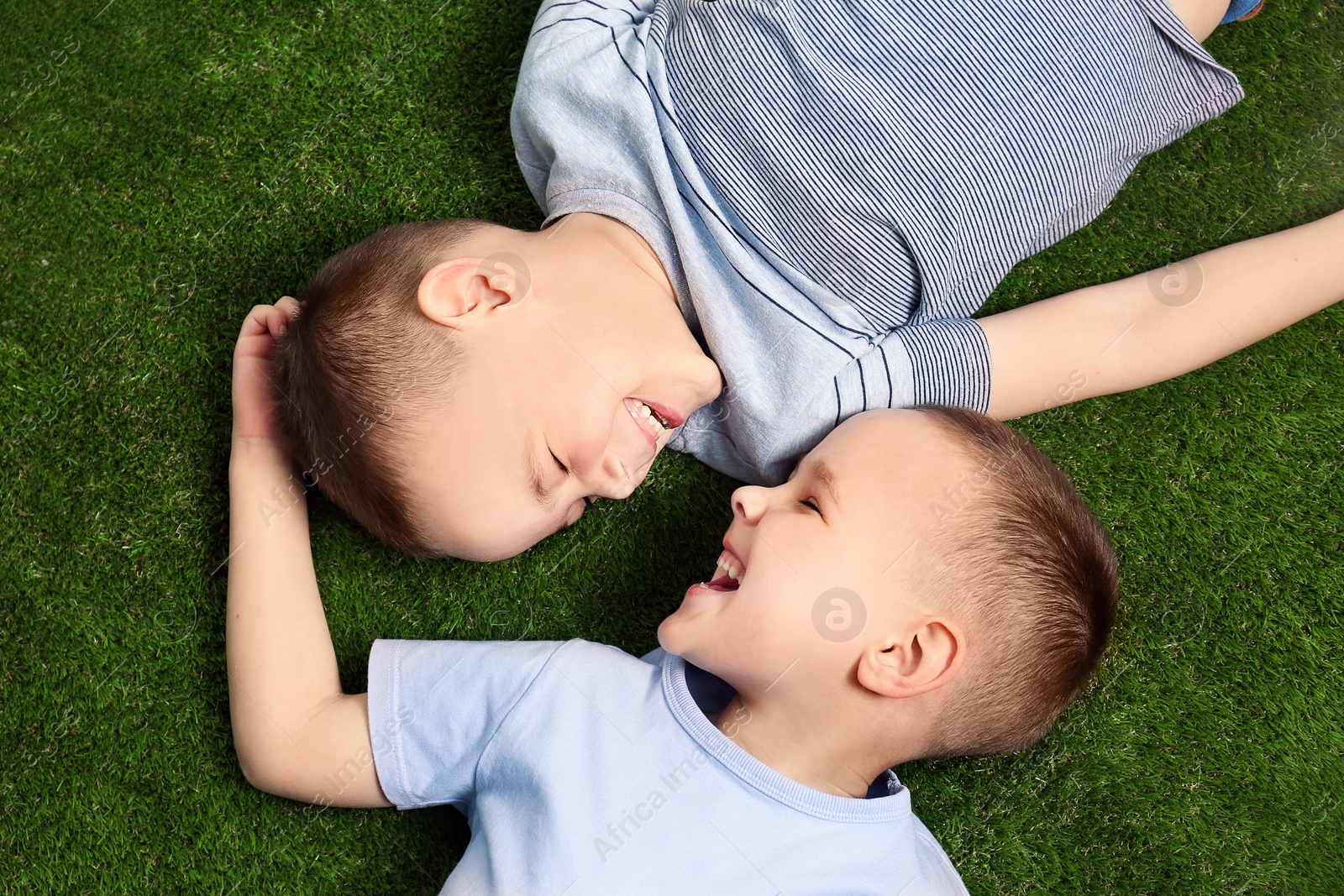 Photo of Portrait of cute twin brothers on green grass, top view