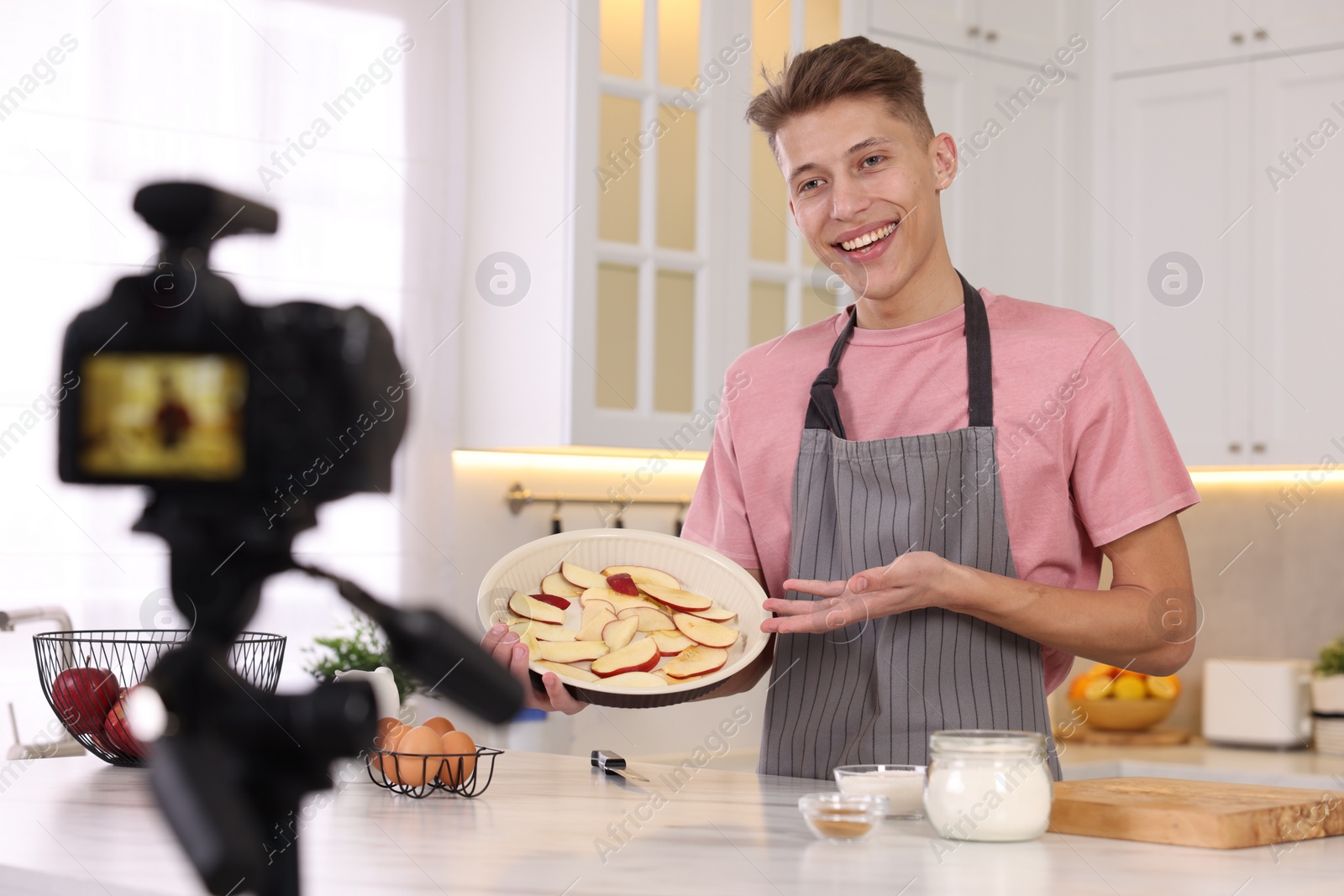 Photo of Smiling food blogger explaining something while recording video in kitchen