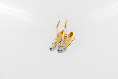 Photo of Stylish sneakers drying on washing line against light grey background