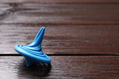 Photo of One blue spinning top on wooden table, closeup. Space for text