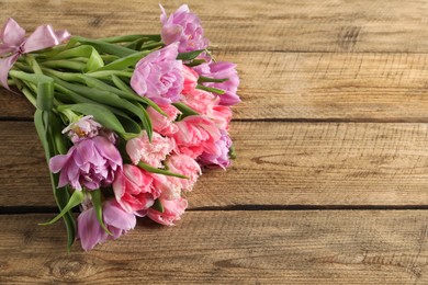 Photo of Beautiful bouquet of colorful tulip flowers on wooden table, space for text