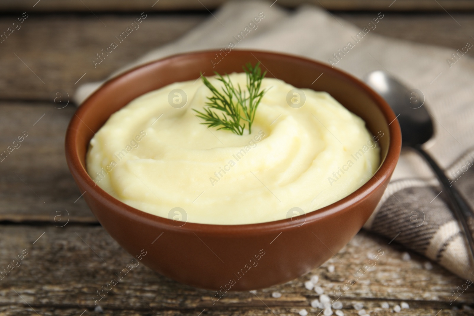 Photo of Freshly cooked homemade mashed potatoes and napkin on wooden table, closeup