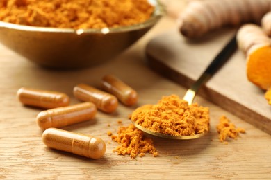 Aromatic turmeric powder and pills on wooden table, closeup