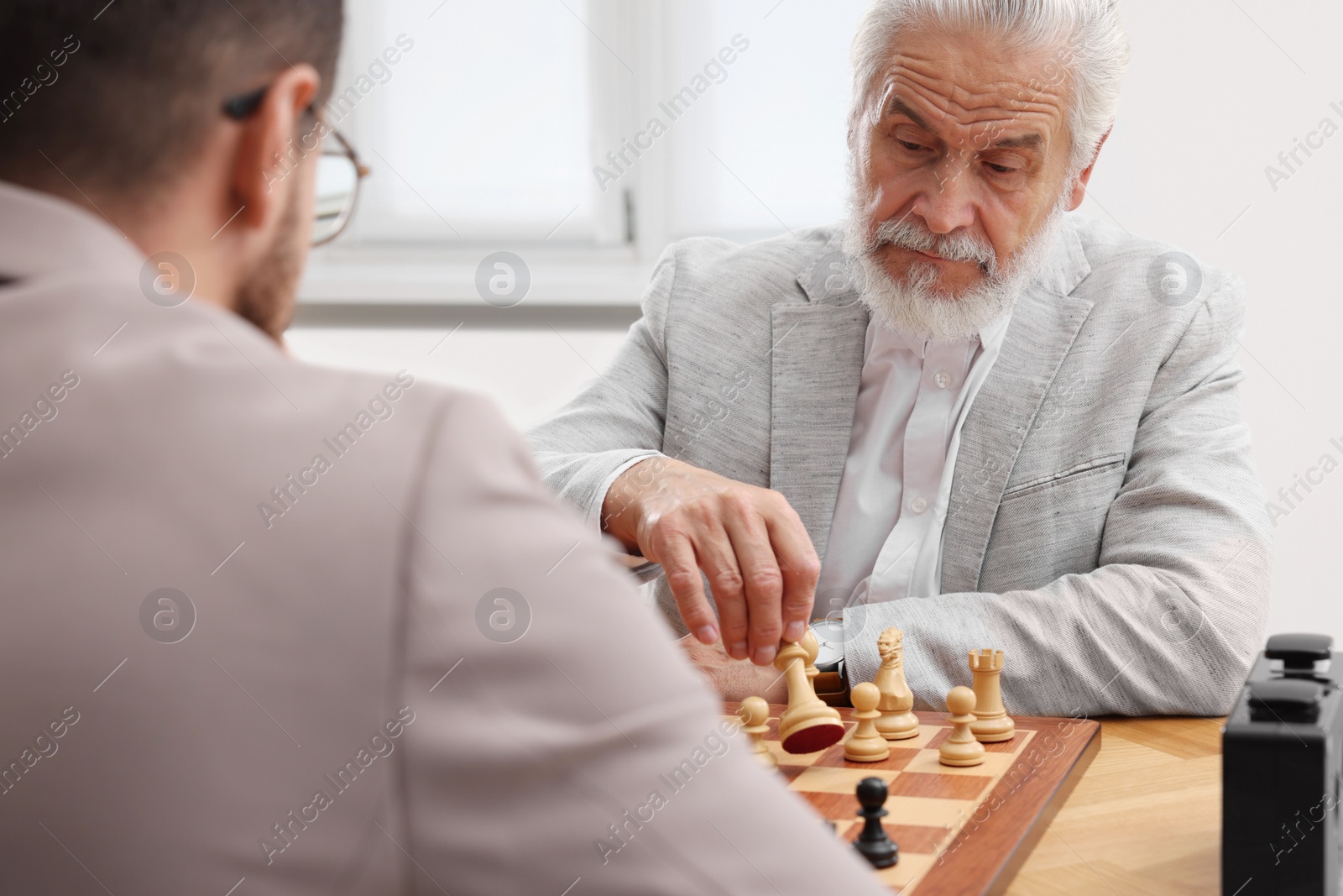 Photo of Men playing chess during tournament at table indoors