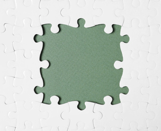 Frame made with white puzzle pieces on grey background, top view. Space for text