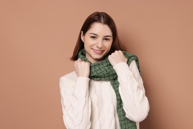 Beautiful woman in warm scarf on brown background