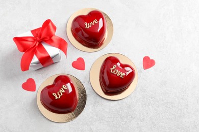 Photo of St. Valentine's Day. Delicious heart shaped cakes and gift on light table, flat lay