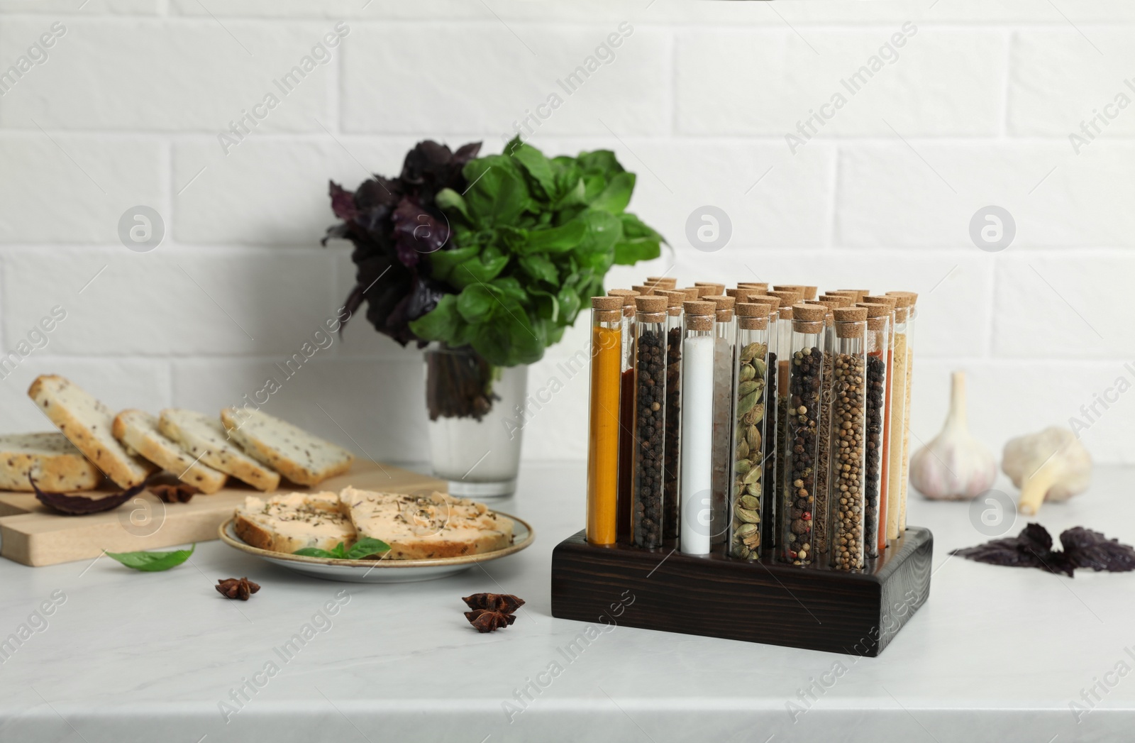 Photo of Glass tubes with different spices and plate of sandwiches on kitchen counter