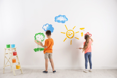 Photo of Little children painting on white wall indoors