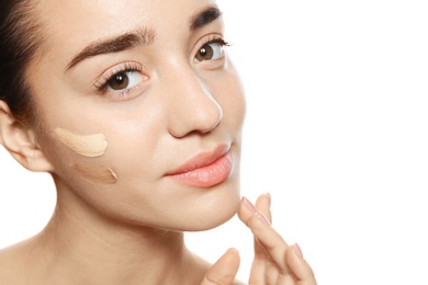 Portrait of young woman with liquid foundation on her face against white background