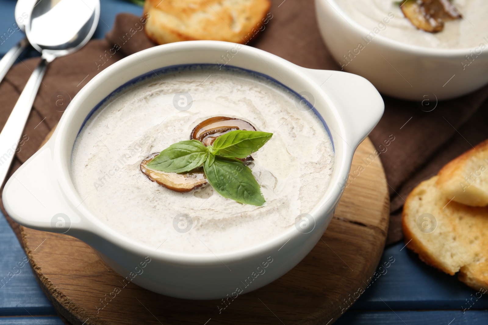 Photo of Fresh homemade mushroom soup served on blue wooden table, closeup