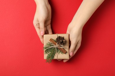 Christmas present. Woman holding beautifully wrapped gift box on red background, top view