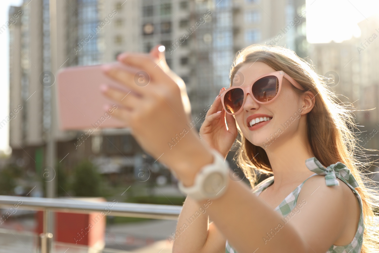 Photo of Beautiful young woman with sunglasses taking selfie outdoors