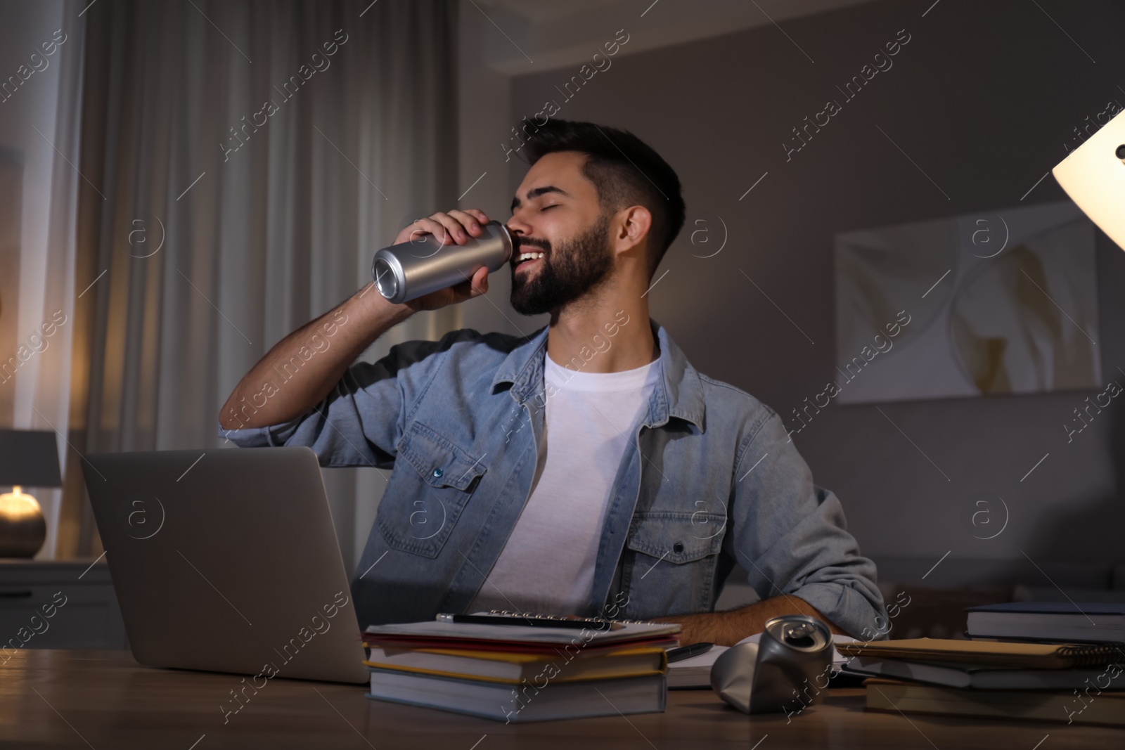 Photo of Young man with energy drink studying at home