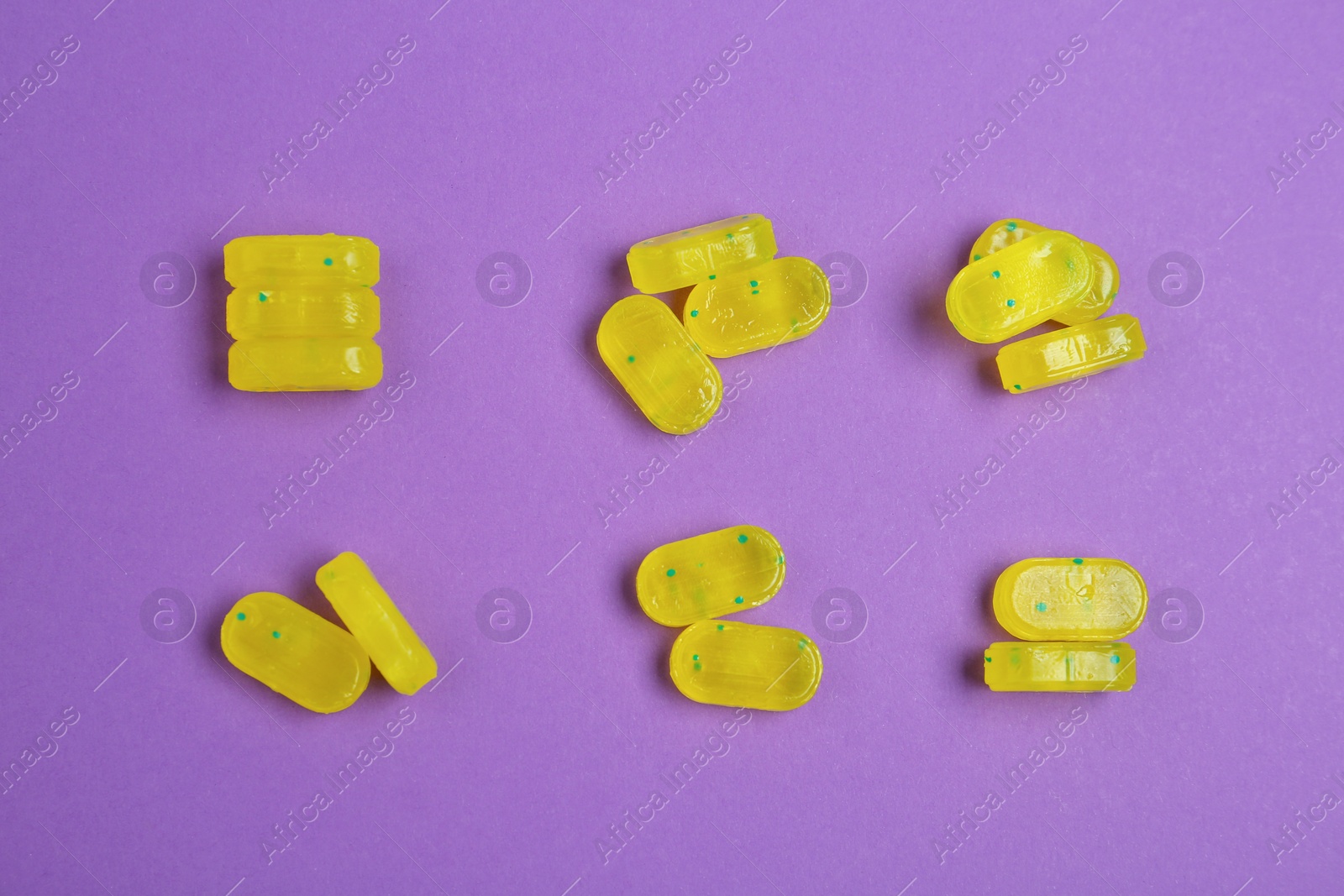 Photo of Tasty lemon drops on purple background, flat lay