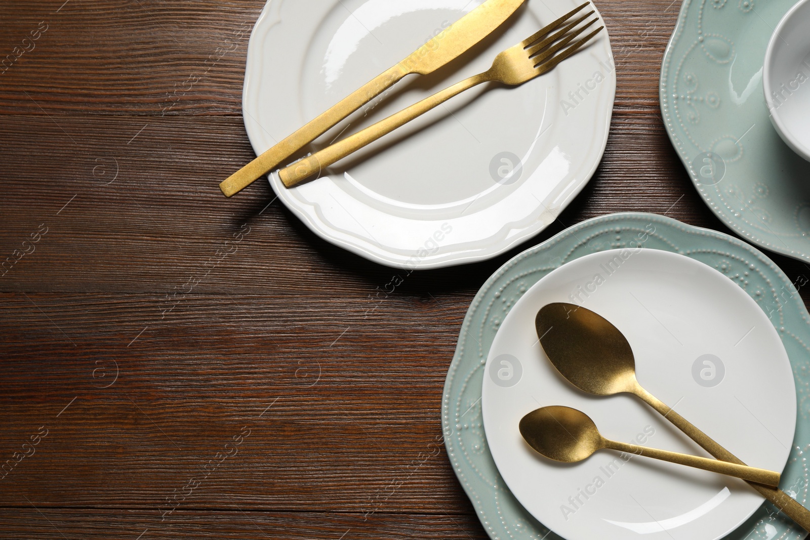 Photo of Beautiful ceramic dishware and cutlery on wooden table, flat lay. Space for text