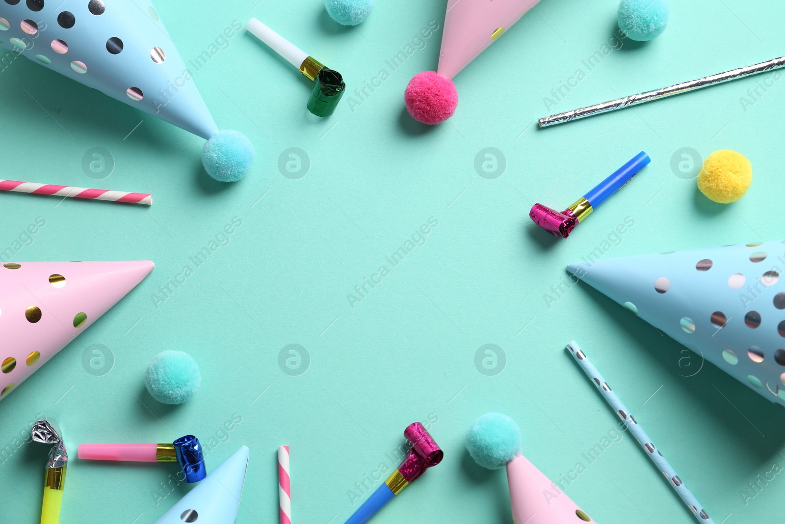 Photo of Frame made of party hats and other bright decor on turquoise background, flat lay. Space for text