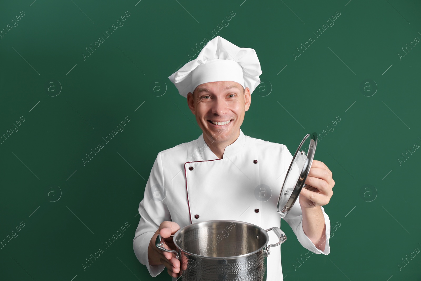 Photo of Happy male chef with cooking pot on dark green background