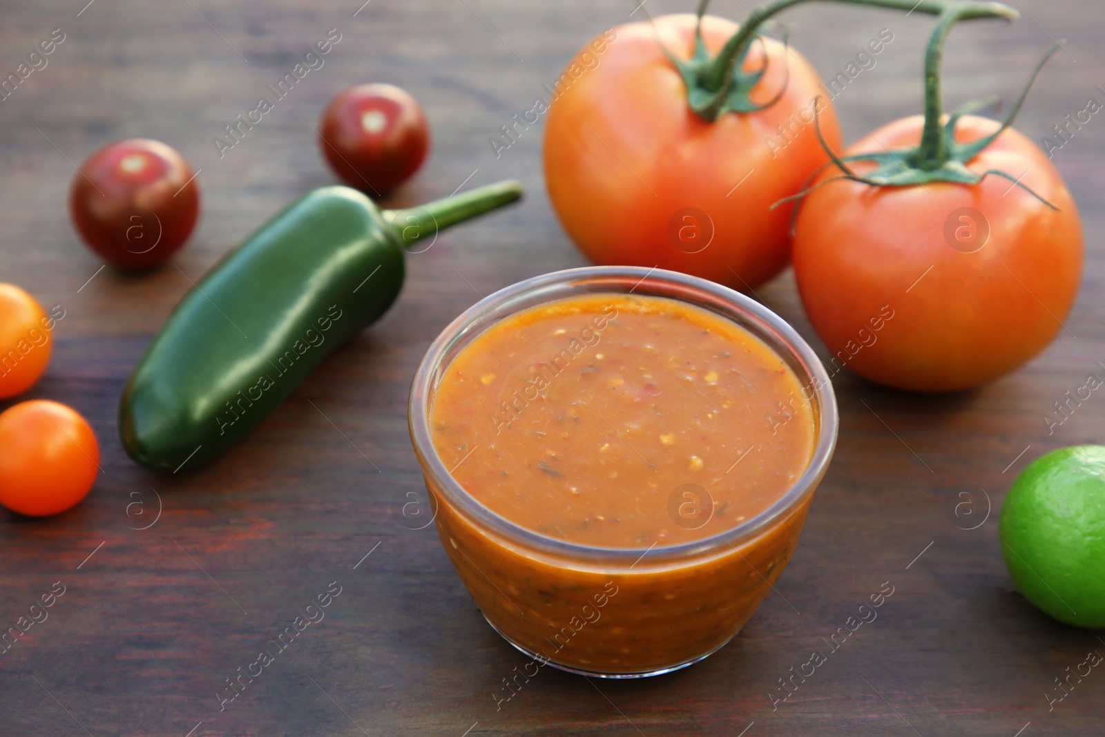 Photo of Tasty salsa sauce and ingredients on wooden table, closeup