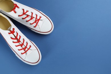 Pair of trendy sneakers on blue background, flat lay. Space for text