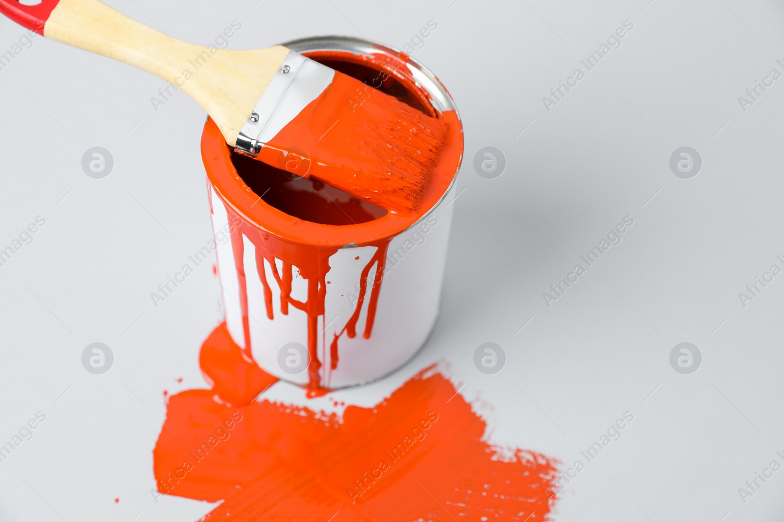 Photo of Can of orange paint and brush on white background. Space for text