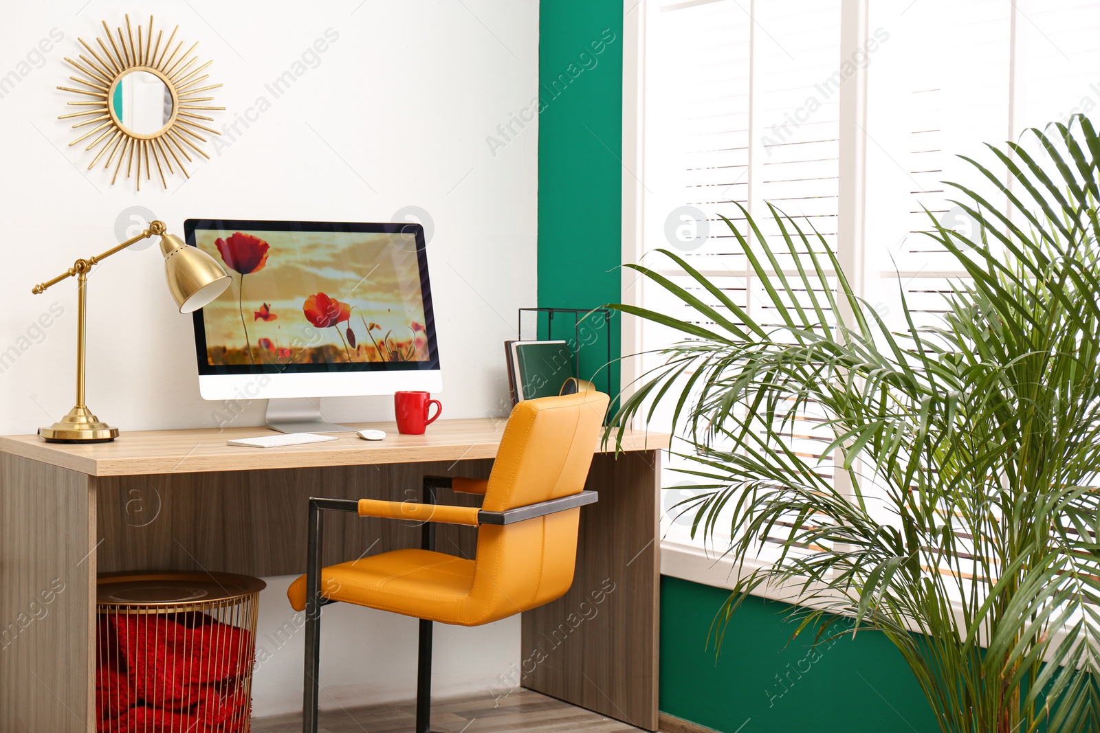 Photo of Comfortable workplace near window with white horizontal blinds in room