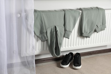 Heating radiator with clothes and shoes in room