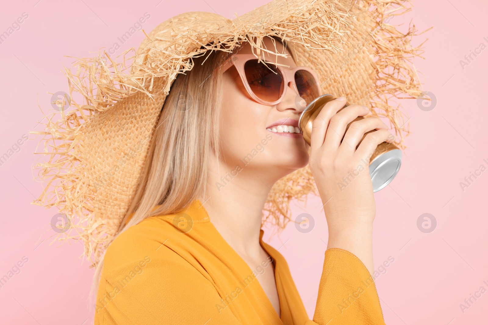 Photo of Beautiful happy woman drinking from beverage can on pink background