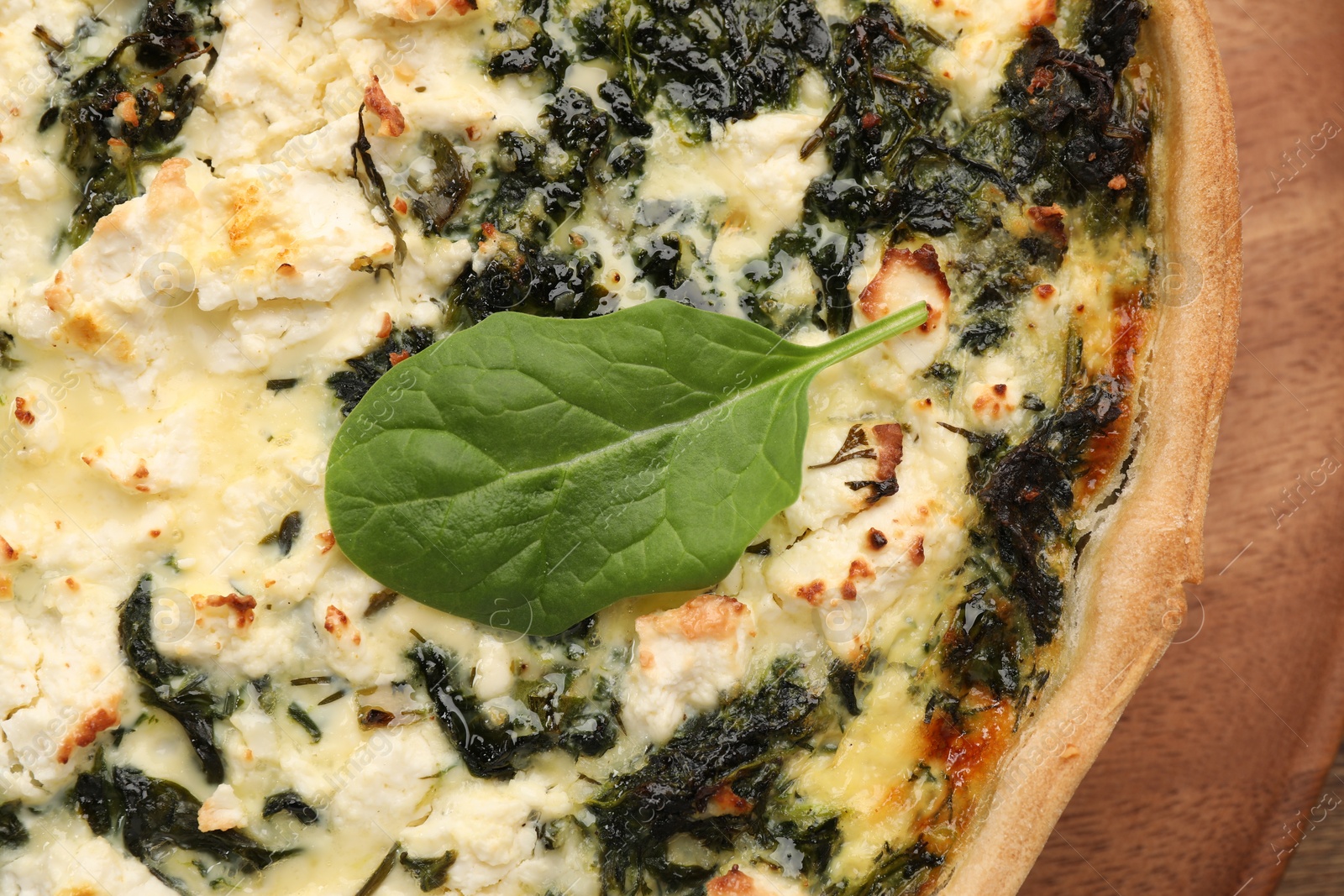 Photo of Delicious homemade spinach quiche on wooden board, closeup