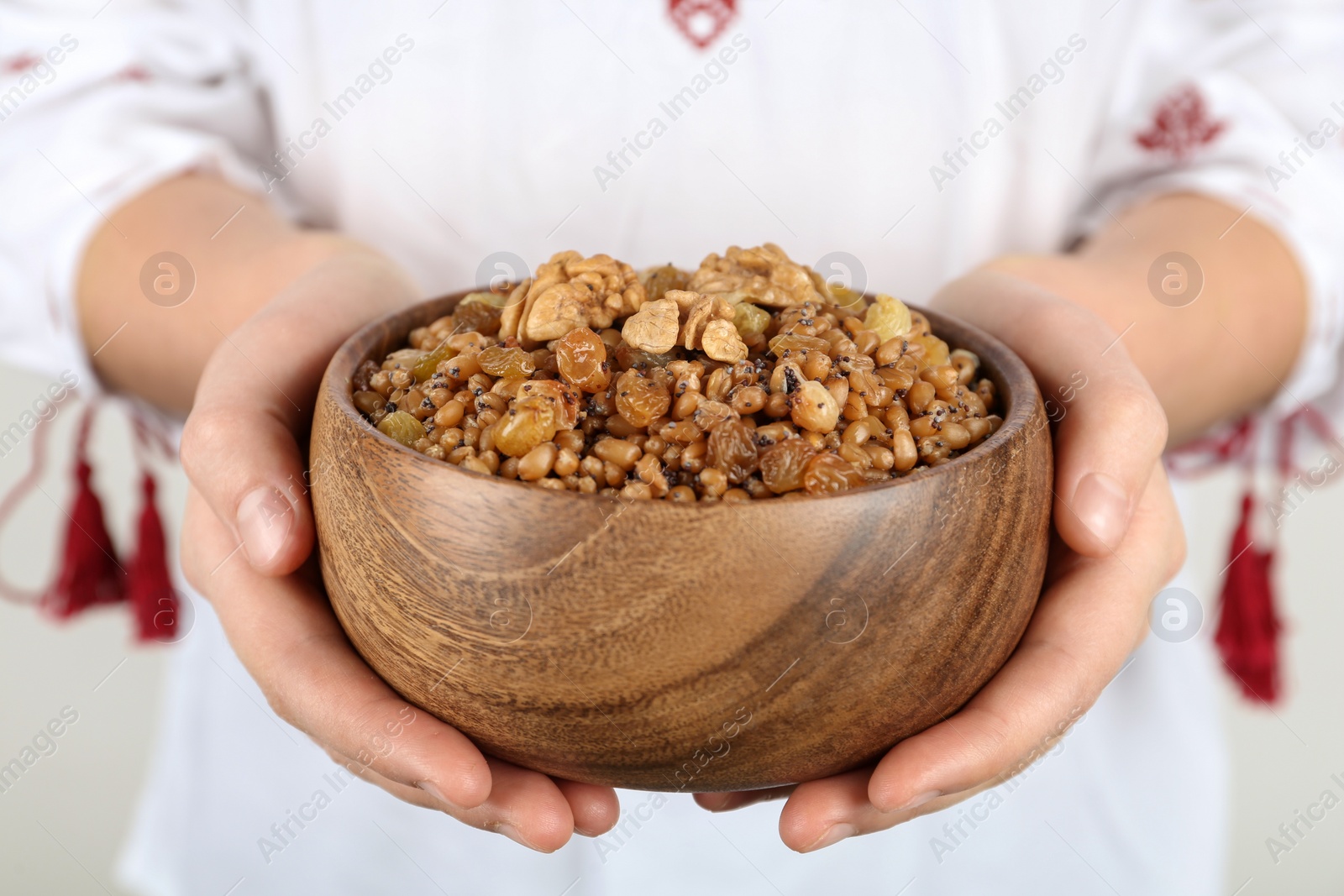 Photo of Woman in slavic shirt holding bowl with traditional kutia, closeup