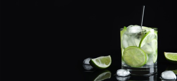 Tasty refreshing soda drink with ice cubes and lime slices on black background. Banner design with space for text