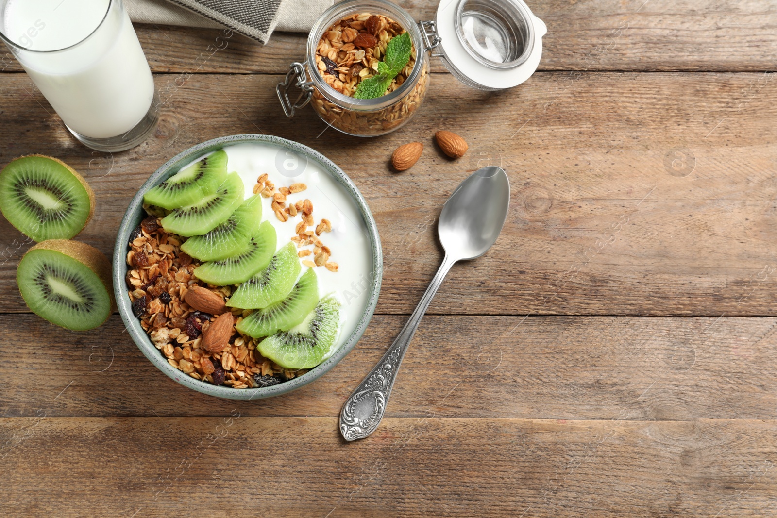 Image of Tasty granola with yogurt and sliced kiwi served for breakfast on wooden table, flat lay. Space for text