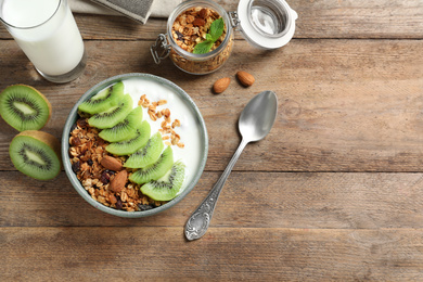 Tasty granola with yogurt and sliced kiwi served for breakfast on wooden table, flat lay. Space for text