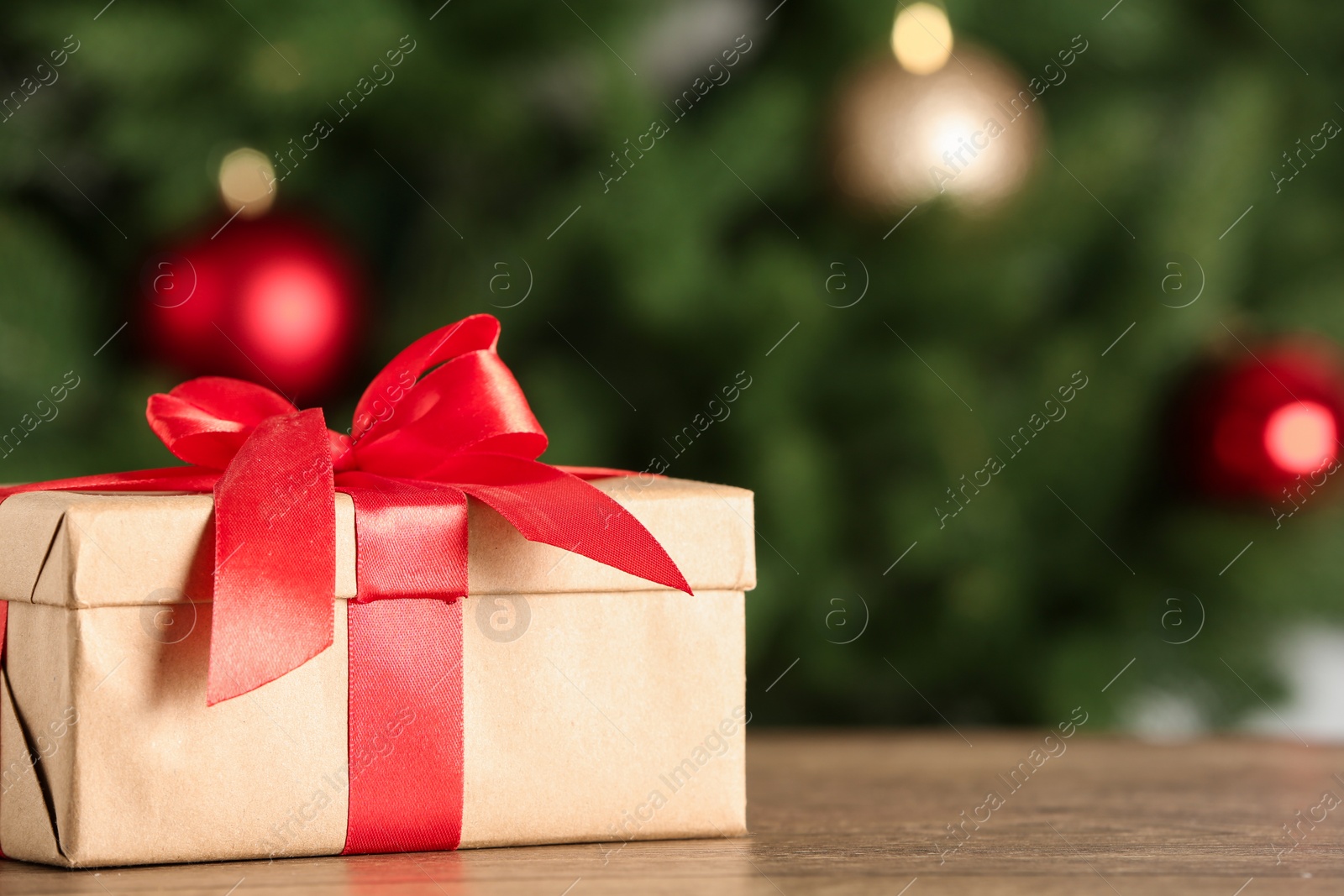 Photo of Christmas gift on table against blurred background. Space for text