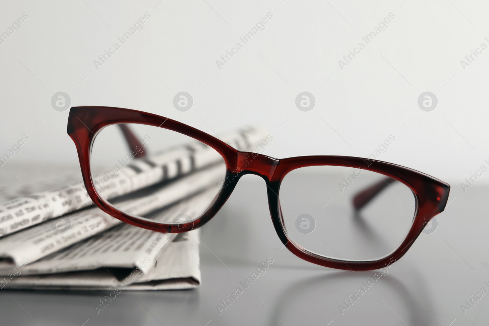 Photo of Newspapers and glasses on grey table, closeup