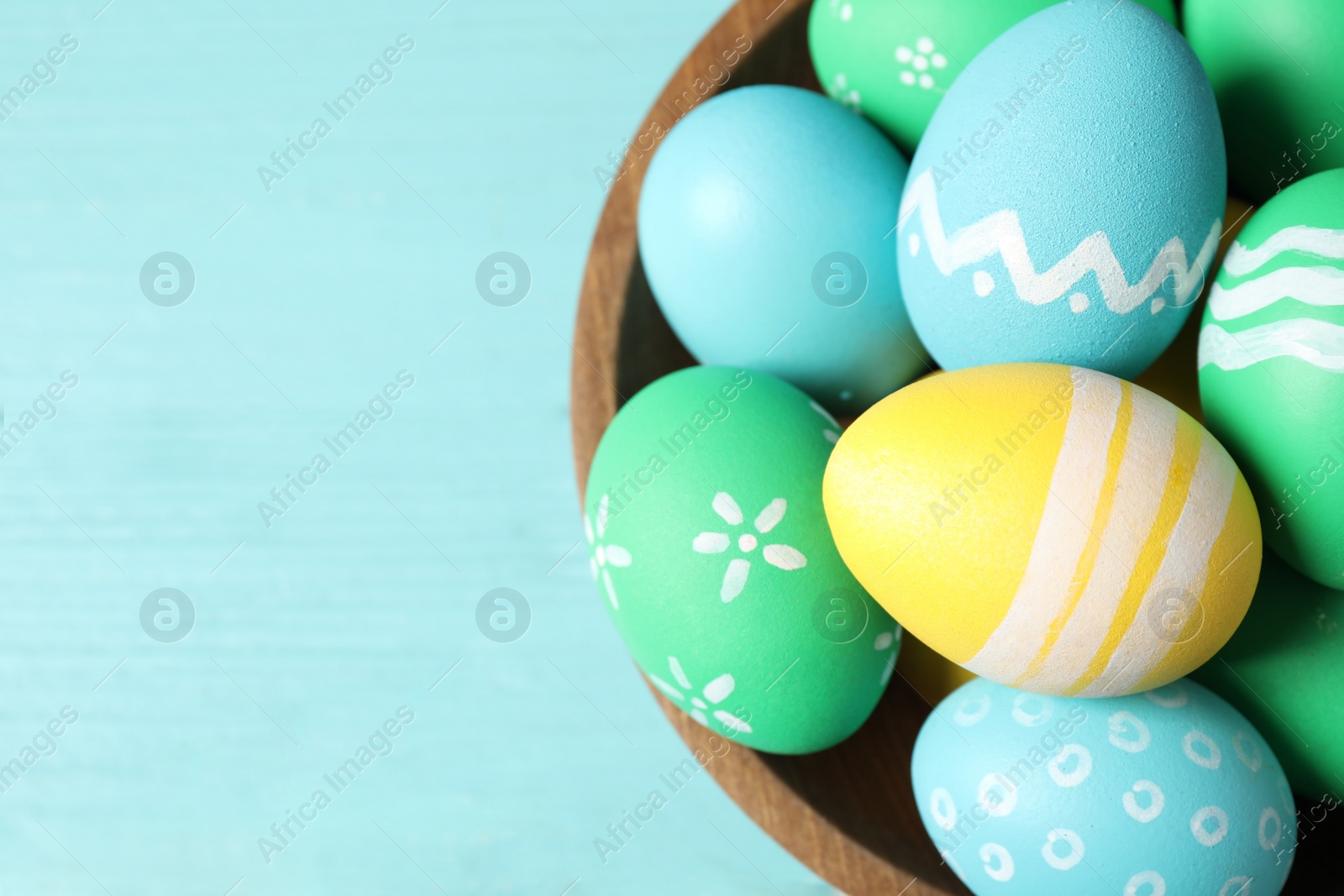 Photo of Colorful Easter eggs on light blue wooden table, top view. Space for text