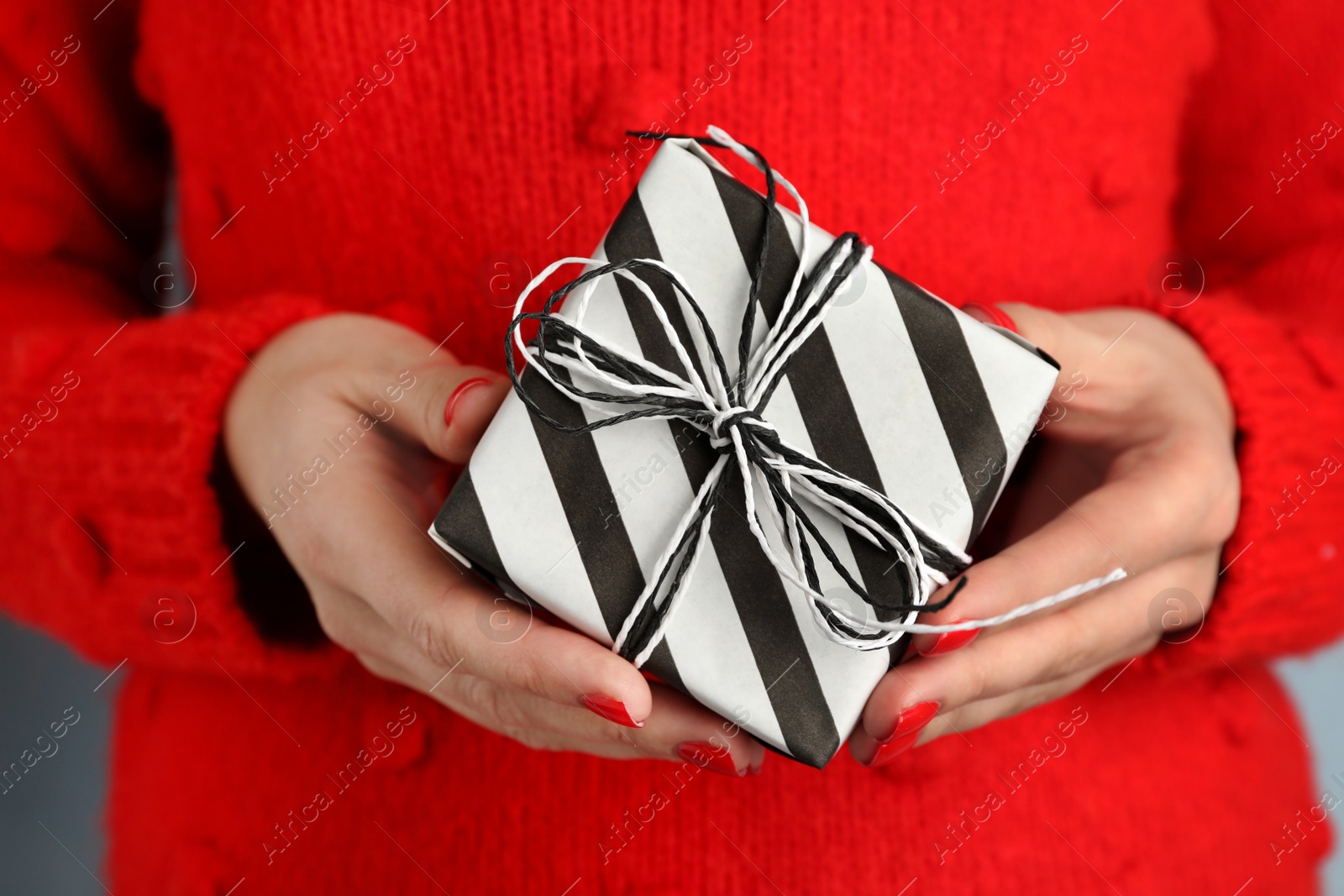 Photo of Young woman holding Christmas gift, closeup view