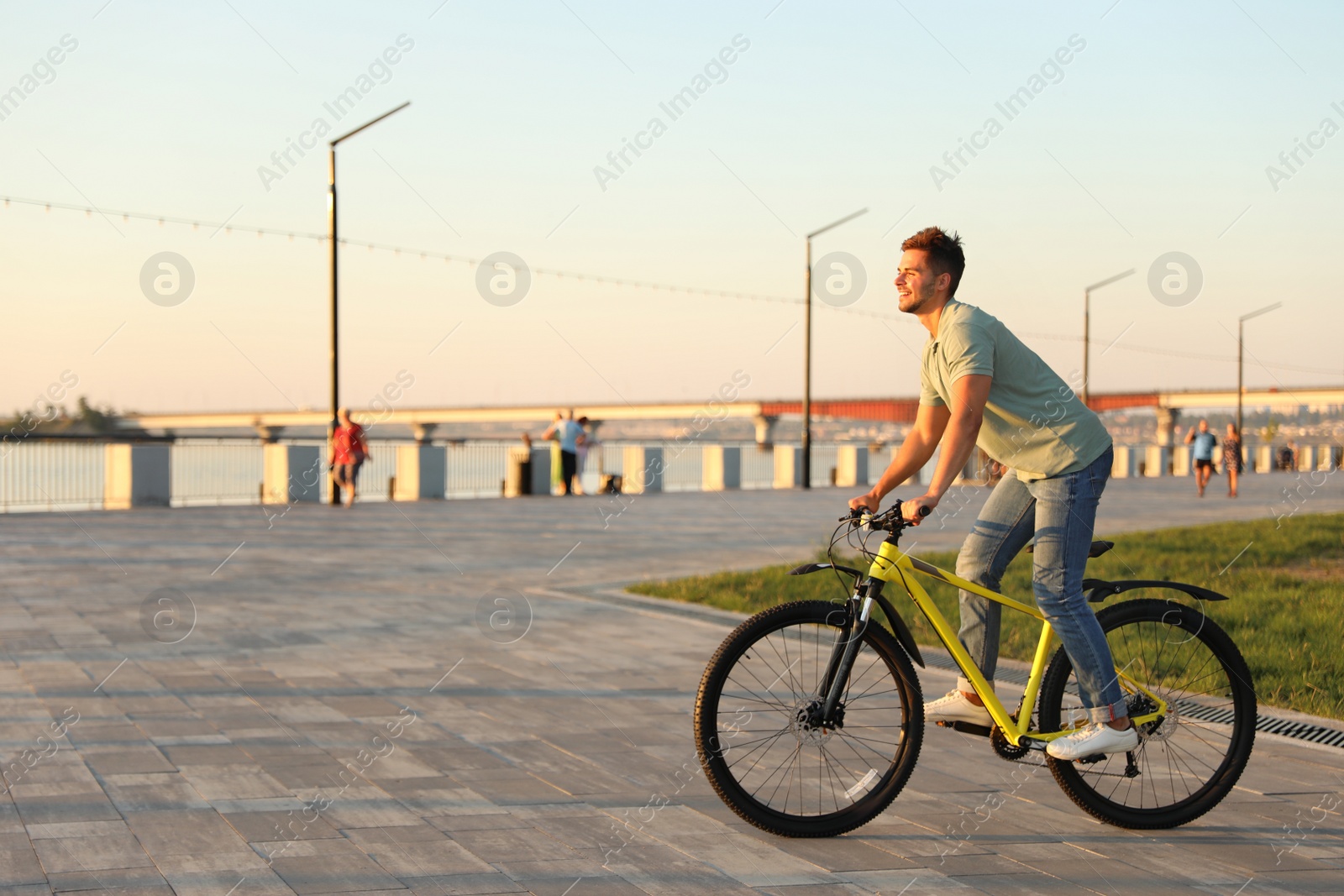 Photo of Handsome young man riding bicycle on city waterfront