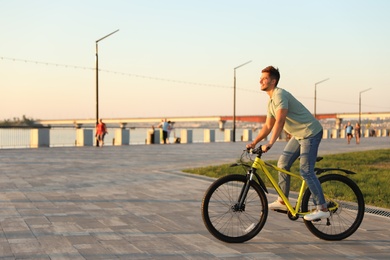 Handsome young man riding bicycle on city waterfront