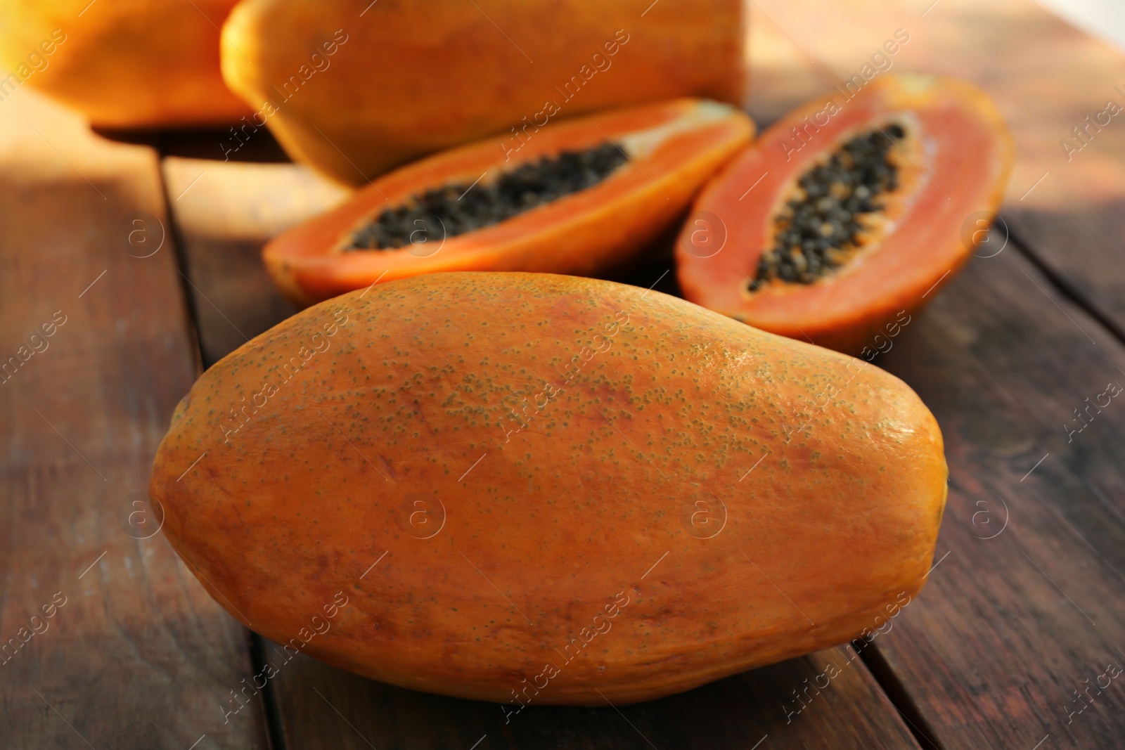 Photo of Fresh ripe cut and whole papaya fruits on wooden table, closeup