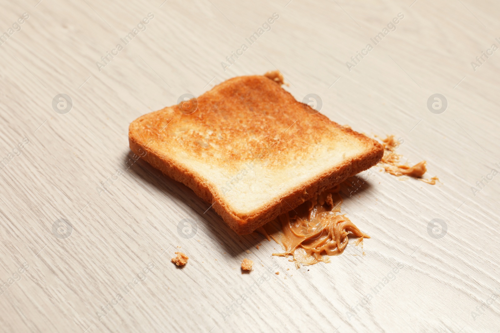 Photo of Overturned toast bread with peanut butter on floor