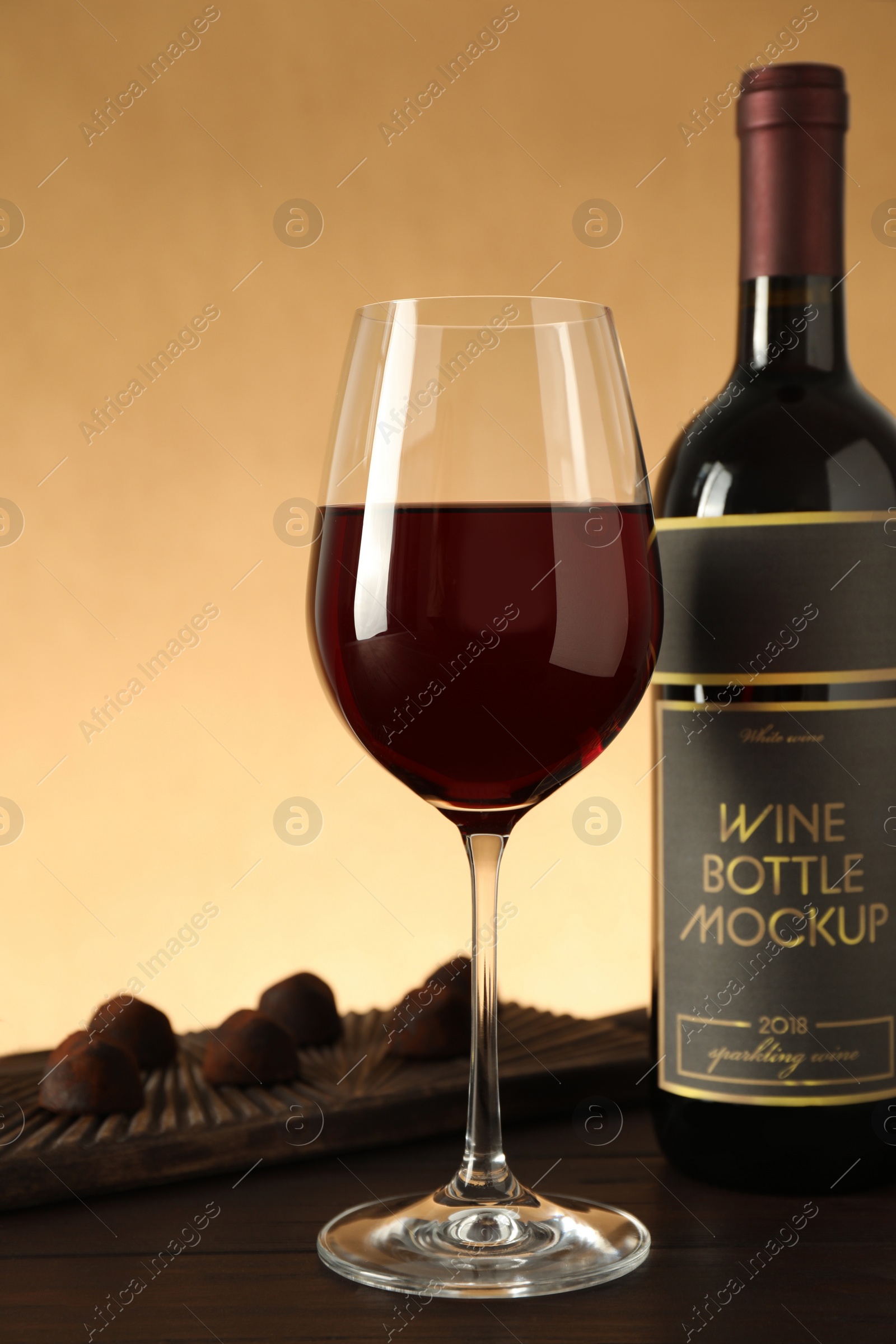 Photo of Bottle and glass of red wine with chocolate candies on wooden table