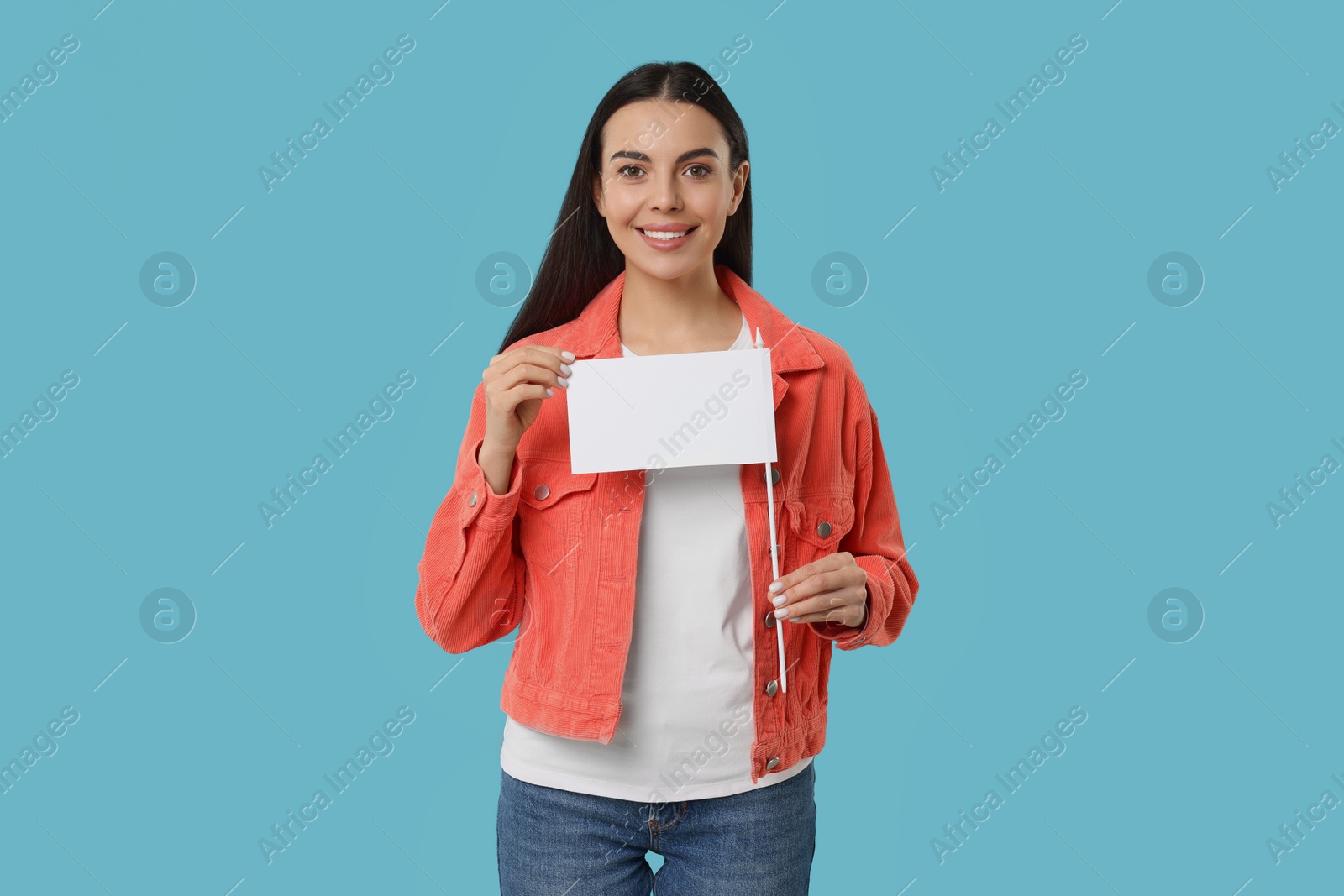 Photo of Happy young woman with blank white flag on light blue background. Mockup for design