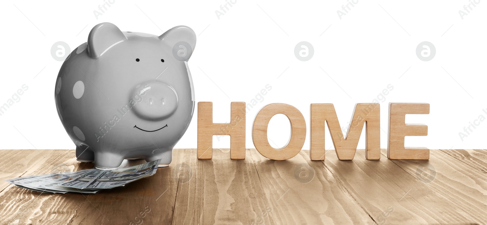 Photo of Piggy bank, word Home and dollar banknotes on wooden table against white background. Saving money concept